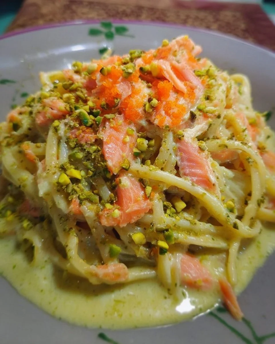 Spaghetti à la crème de parmesan, pesto de pistache et saumon sur une assiette